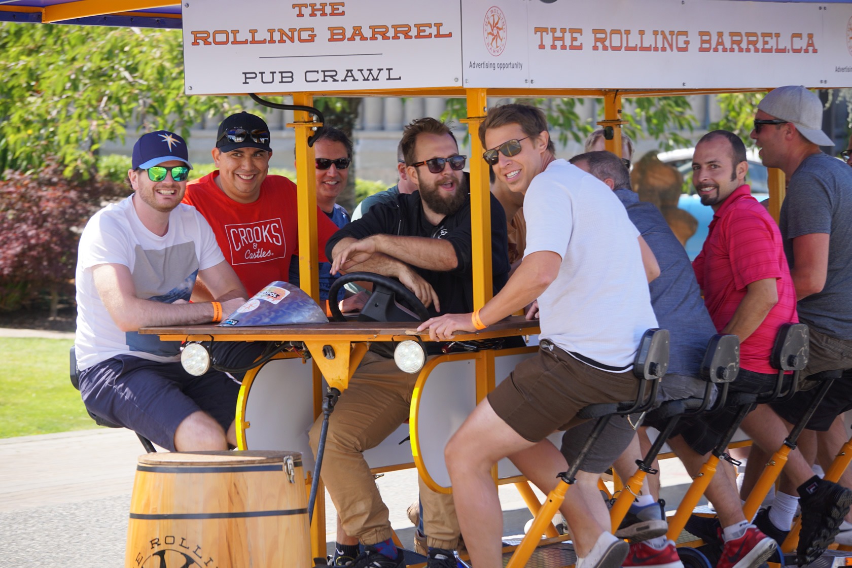 A group of happy men on tour and pedaling The Rolling Barrel vehicle with “Captain Mike” at the helm.